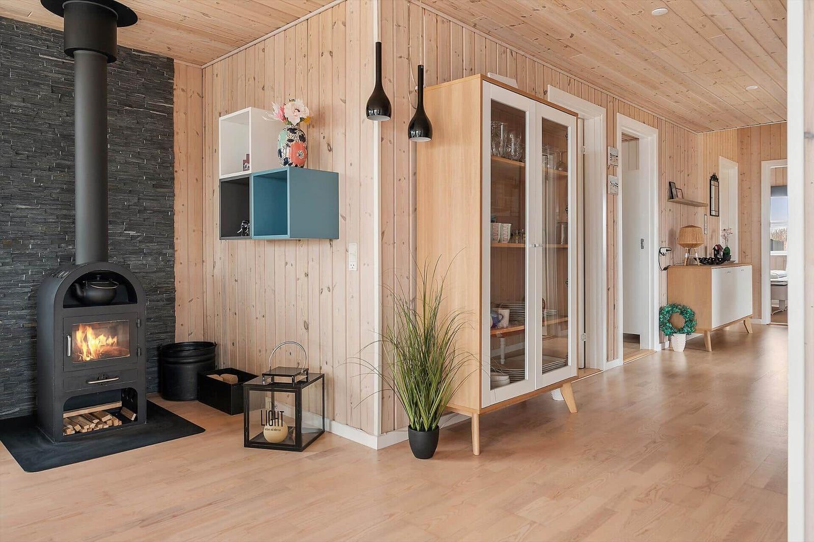 Living area with wood paneling, fireplace, and glass-front cabinet.
