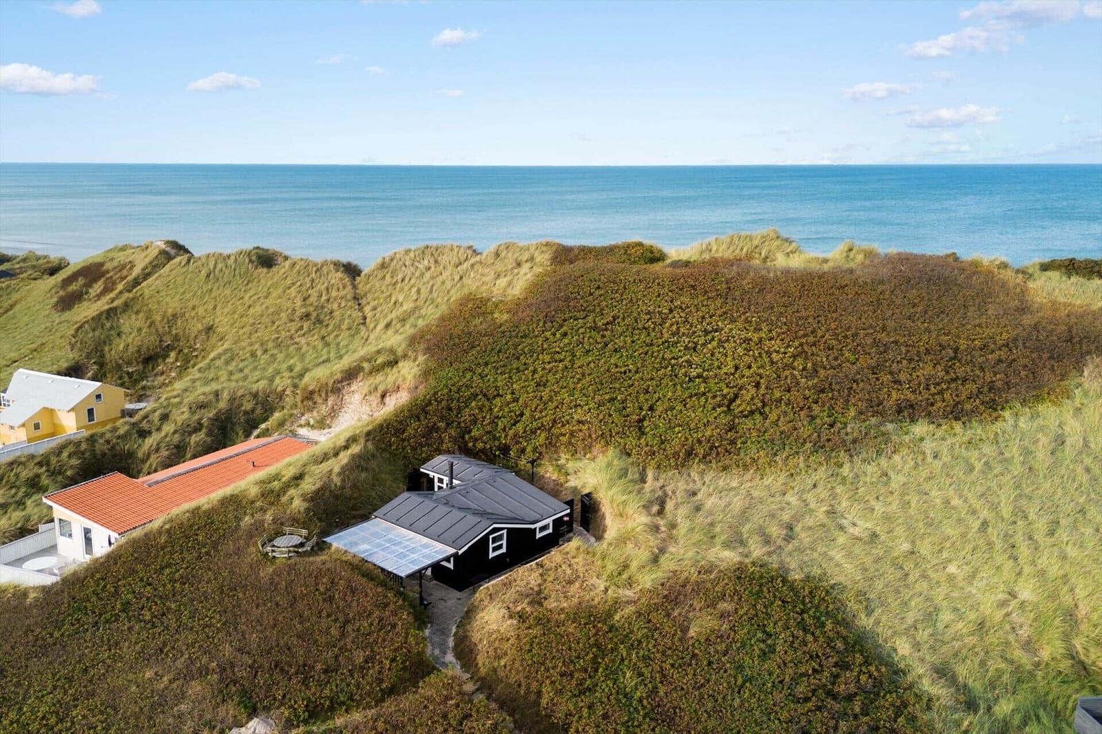 Schwarzes Haus mit Solarium auf Dünen, Blick auf das Meer.