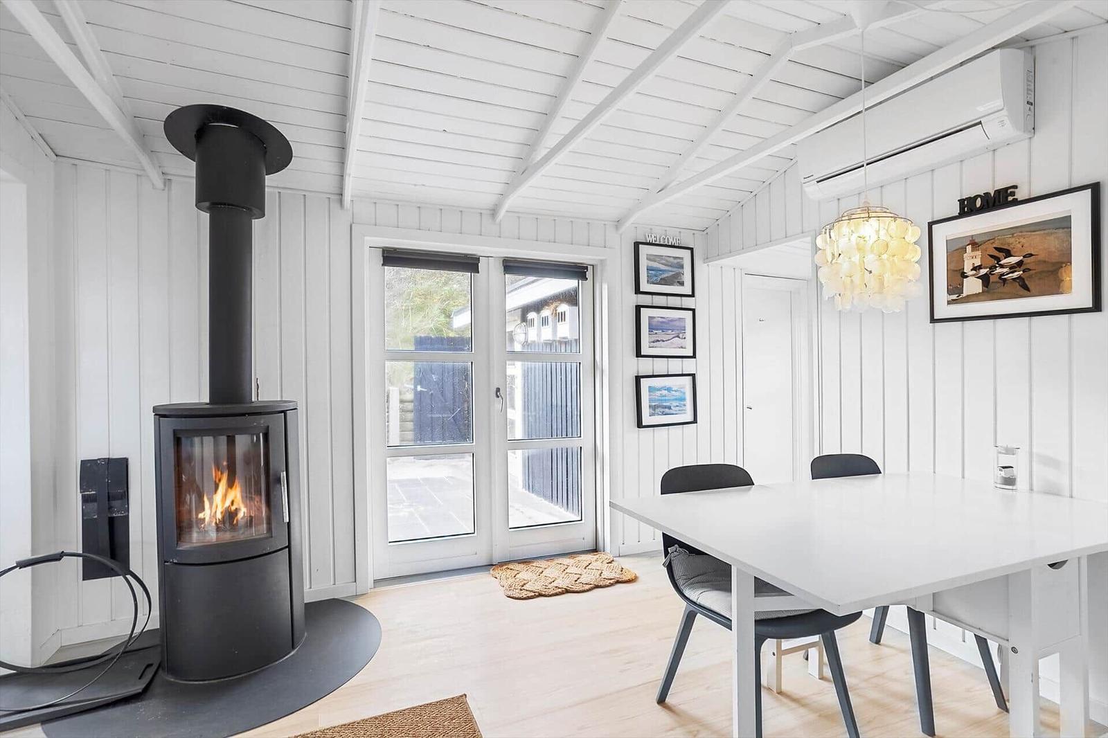 Raum mit Esstisch, Kamin und Glastüren zur Terrasse