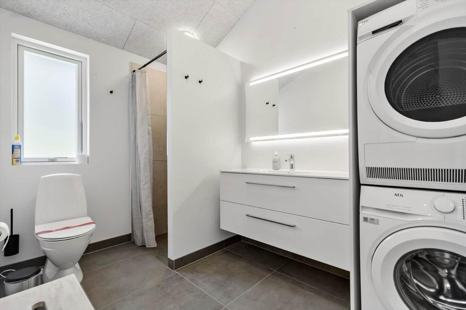 Bathroom with toilet, shower, and washer-dryer combination.