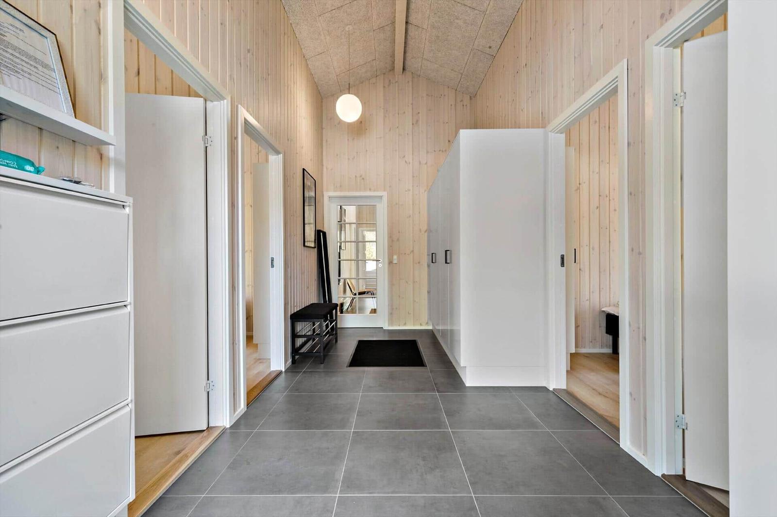 Long hallway with wooden wall cladding and gray floor tiles.