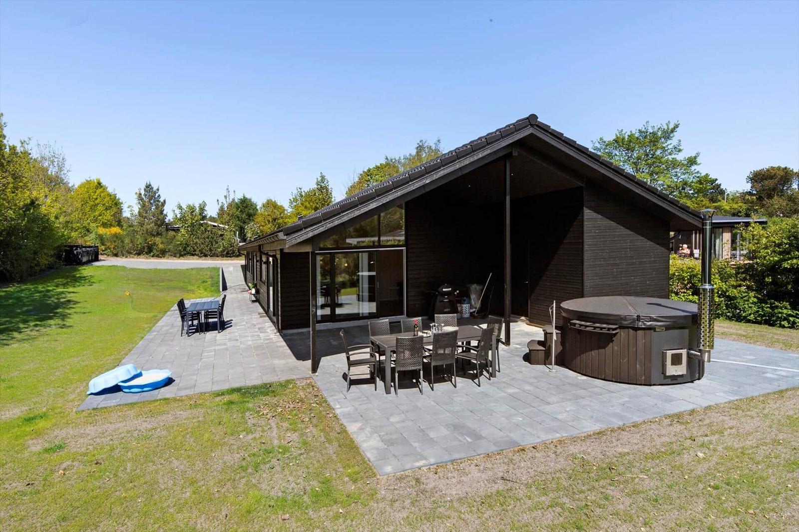 Modern wooden house with terrace, hot tub, and garden.
