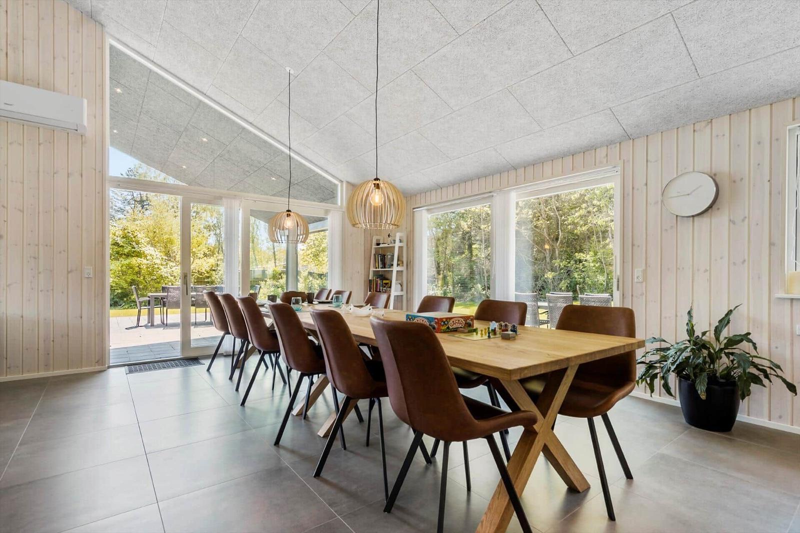 Dining room with wooden table, brown chairs, and large windows to the outdoor terrace.