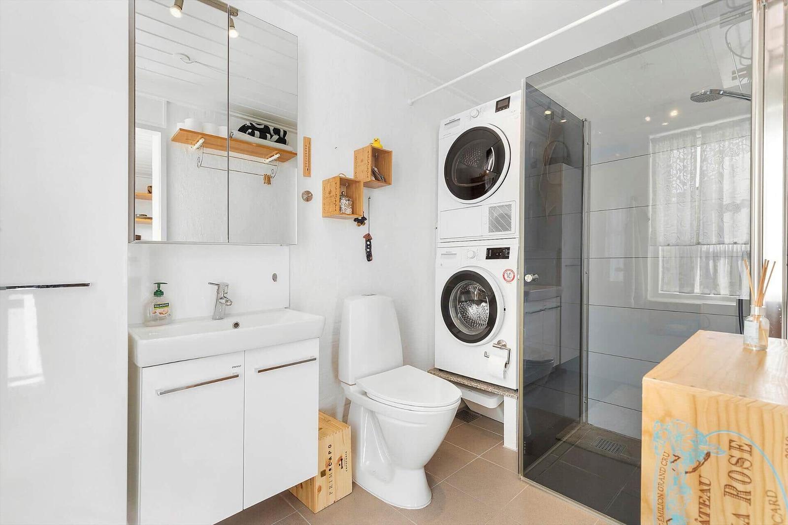 Bathroom with washing machine, dryer, toilet, and shower.