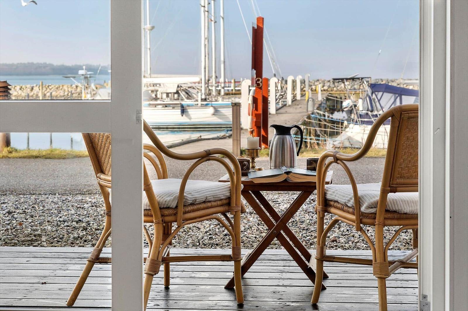 Terrace with two chairs and table. View of harbor with boats.