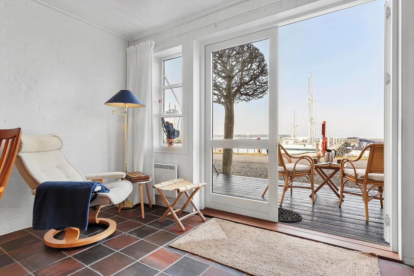 Room with seating and view to terrace with garden furniture and harbor view.