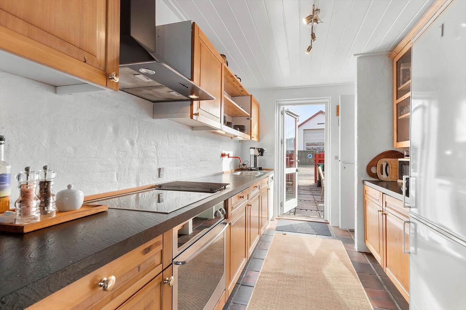Kitchen with wooden cabinets, stone countertop, and view to terrace
