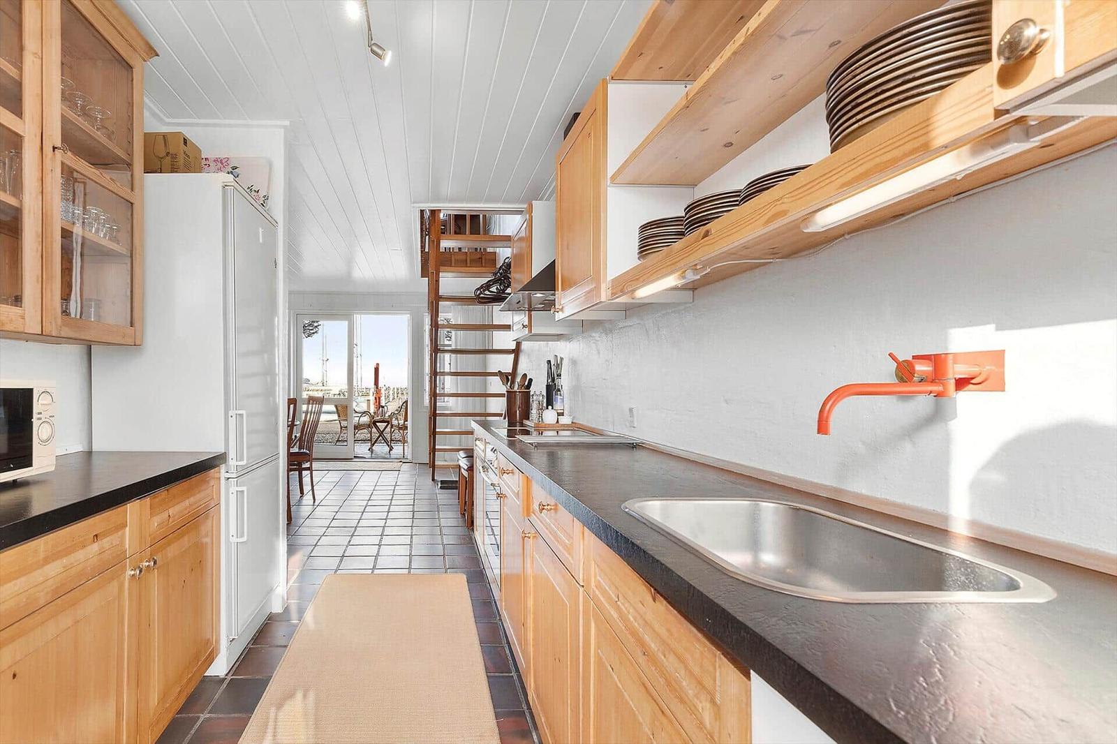 Kitchen with wooden cabinets, countertop, and view of terrace.