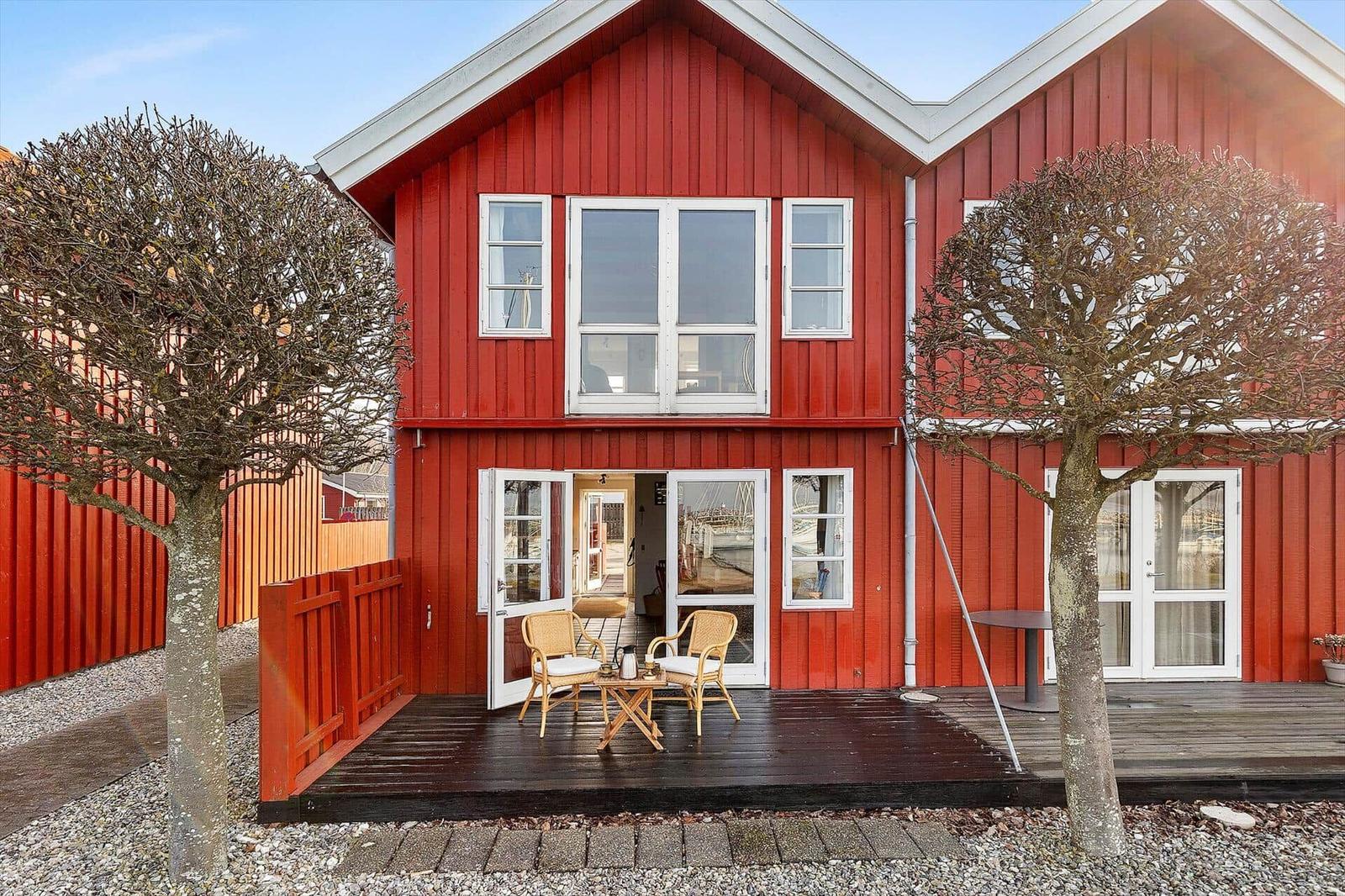 Red wooden house with terrace and garden. Windows and doors are white.