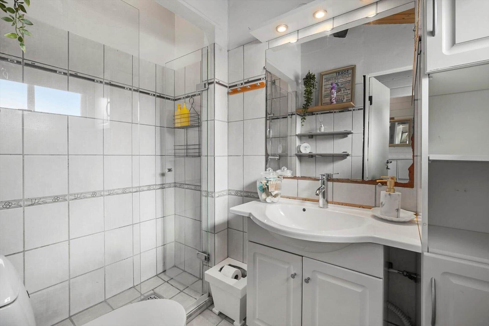 Badezimmer mit Dusche, Waschbecken und Spiegelschrank.