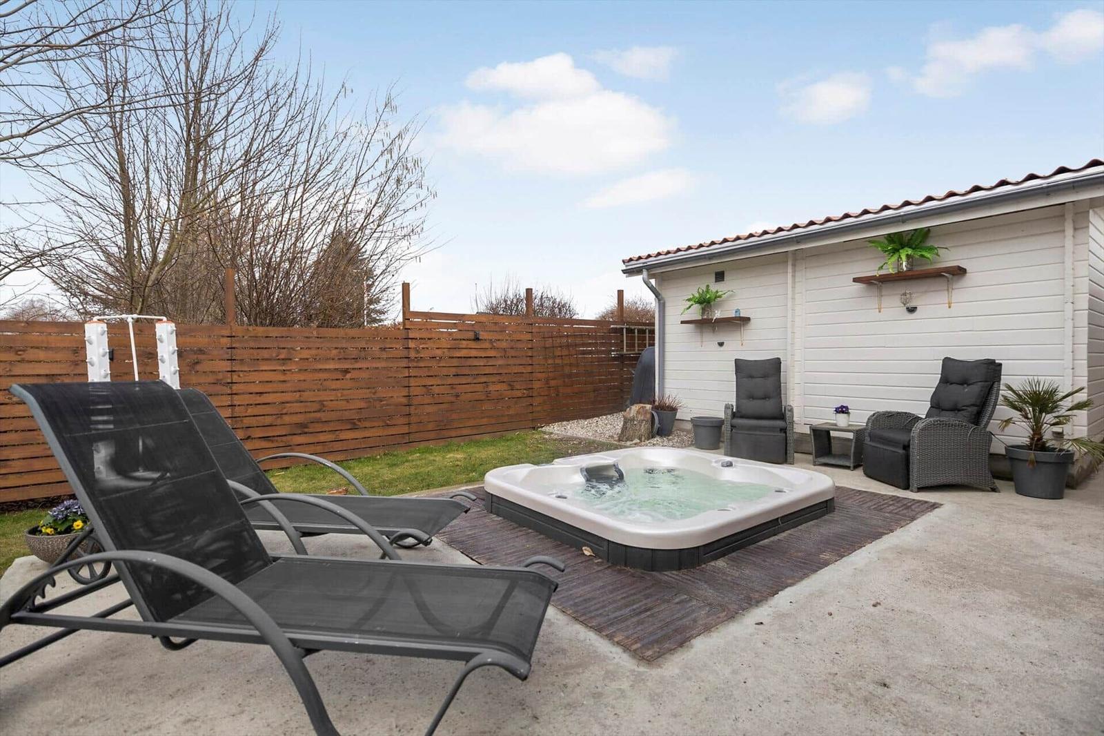 Hinterhof mit Whirlpool, Liegestühlen und Sitzgelegenheiten an Hauswand.
