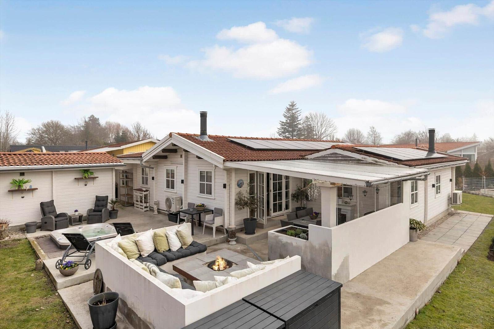 Haus mit Terrasse, Sitzgelegenheiten und Feuerkorb im Freien.