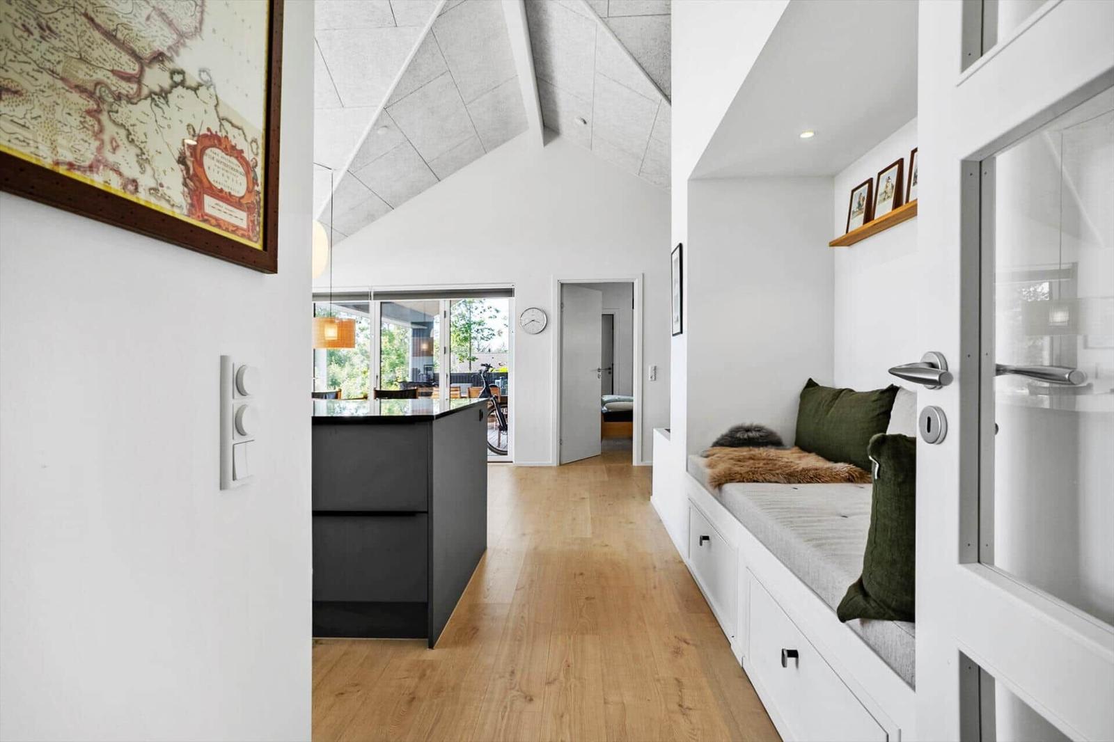 Helle Wohnung mit Sitzbank, Holzboden und geradem Deckenverlauf.