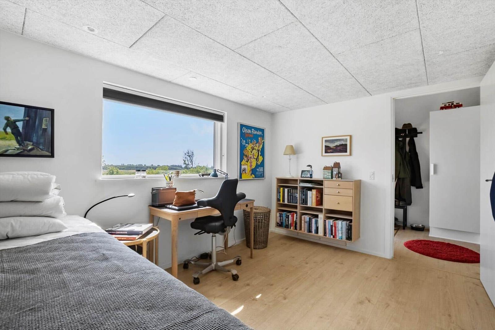 Schlafzimmer mit Schreibtisch, Bücherregal und Blick auf die Landschaft.