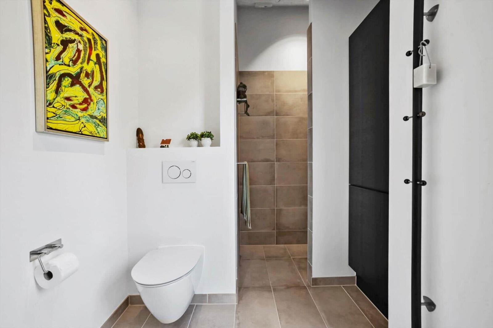 Badezimmer mit Toilette, Dusche und Wandbild.