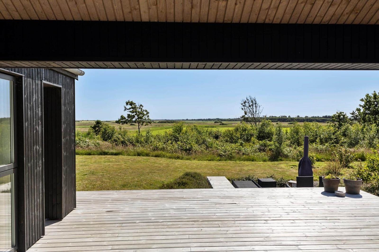 Terrasse mit Holzdecke und Blick auf grüne Landschaft.