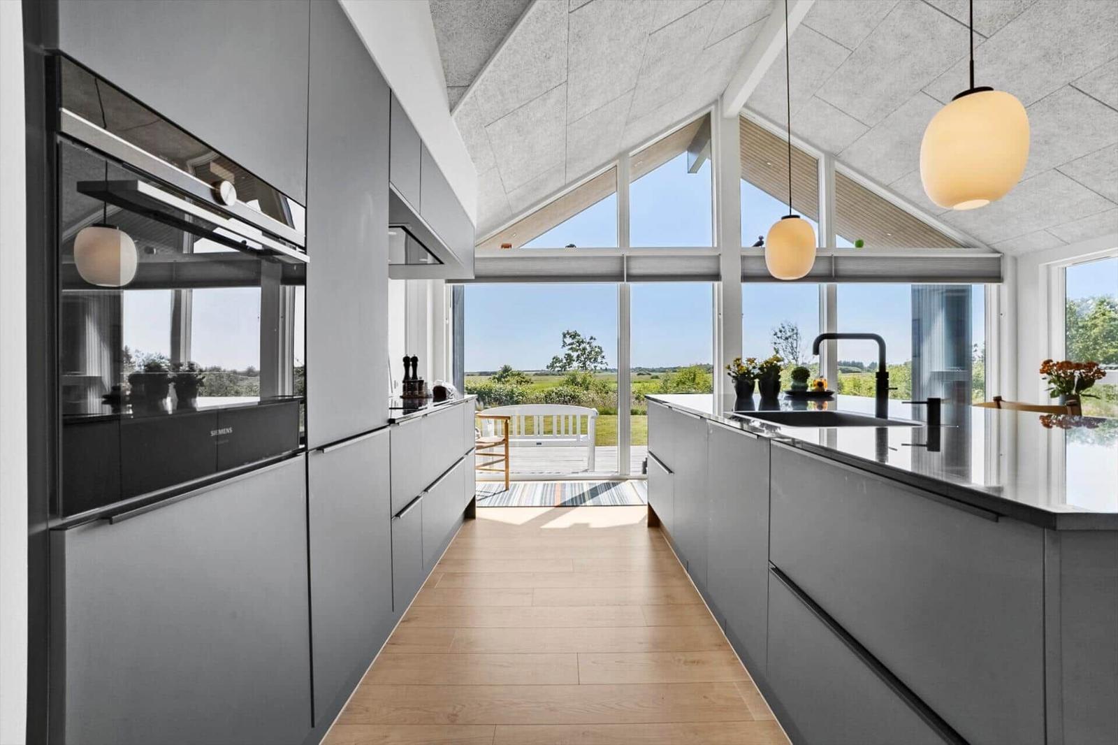 Moderne Küche mit Blick auf Terrasse und Landschaft.