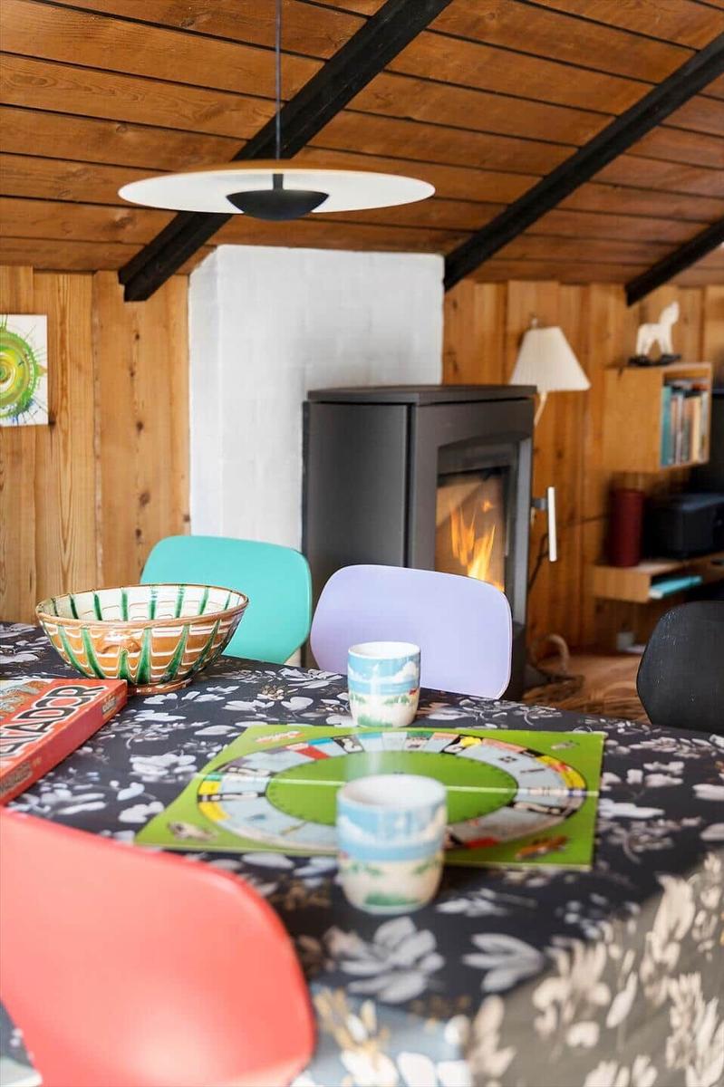 Tisch mit Spiel und Bechern unter Holzdecke mit Kamin.