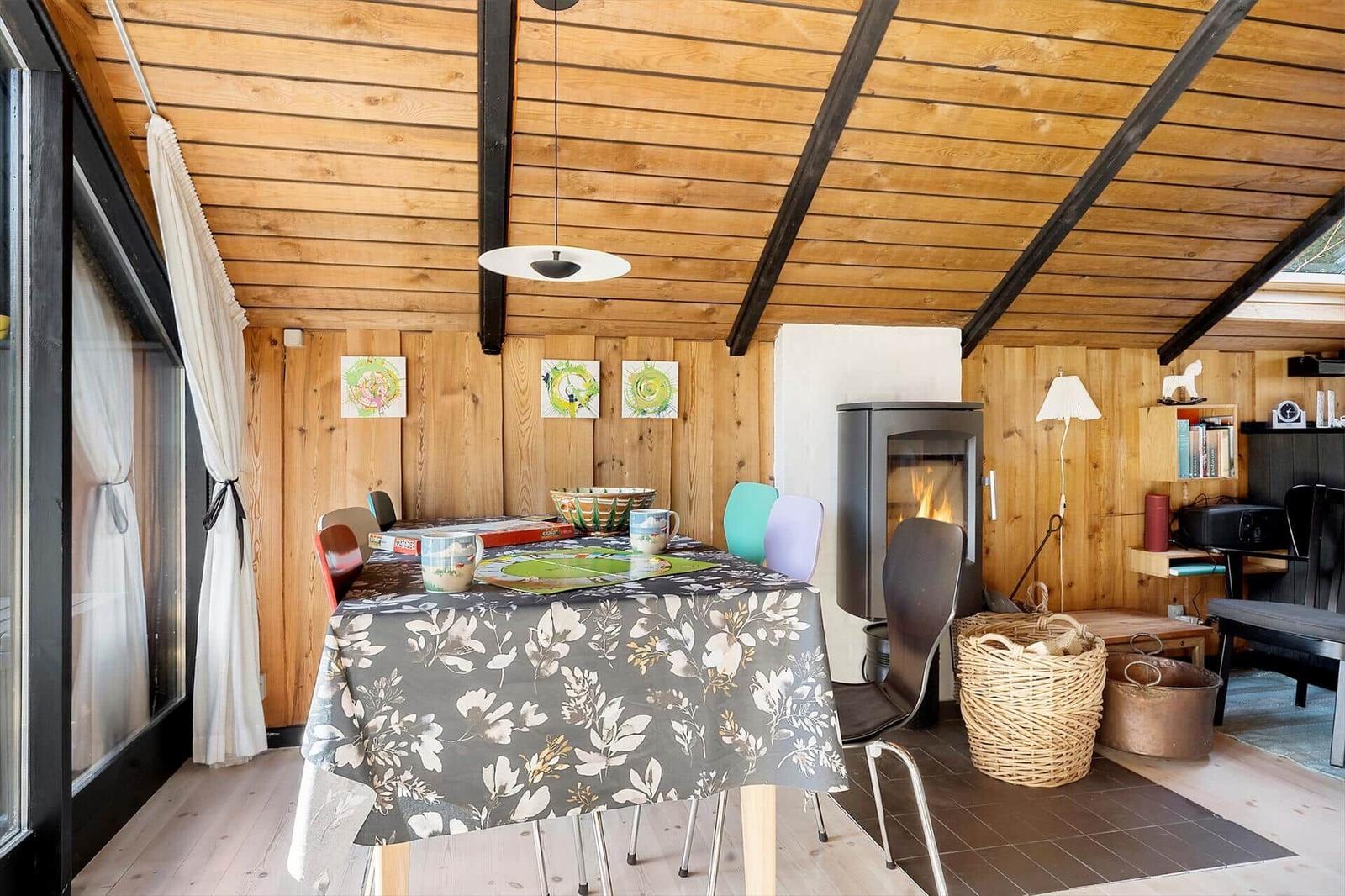 Esszimmer mit Holzwand, Kamin und Tisch mit Tischdecke.