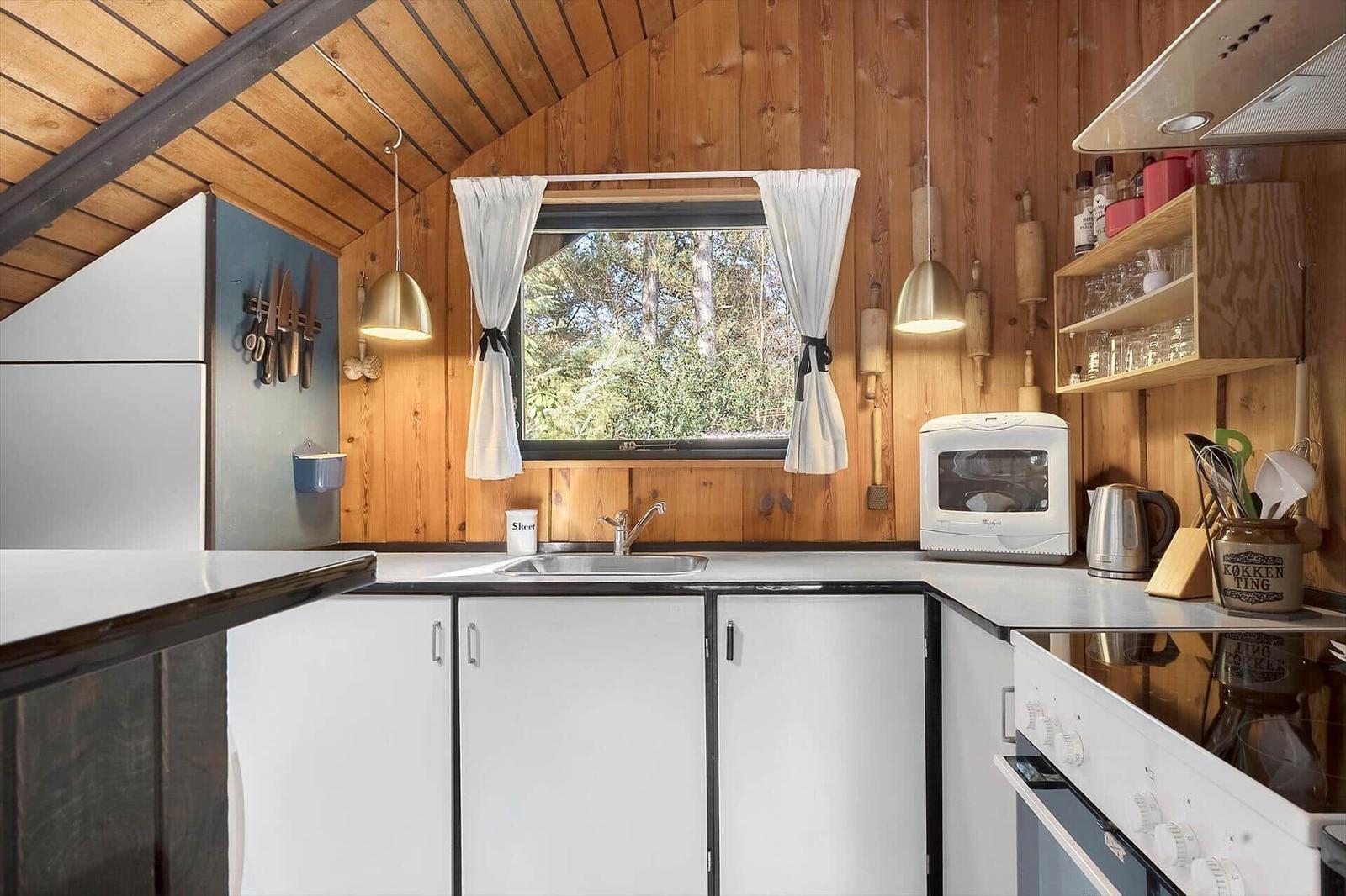 Küche mit Holzwand, Fenster und weißen Schränken.