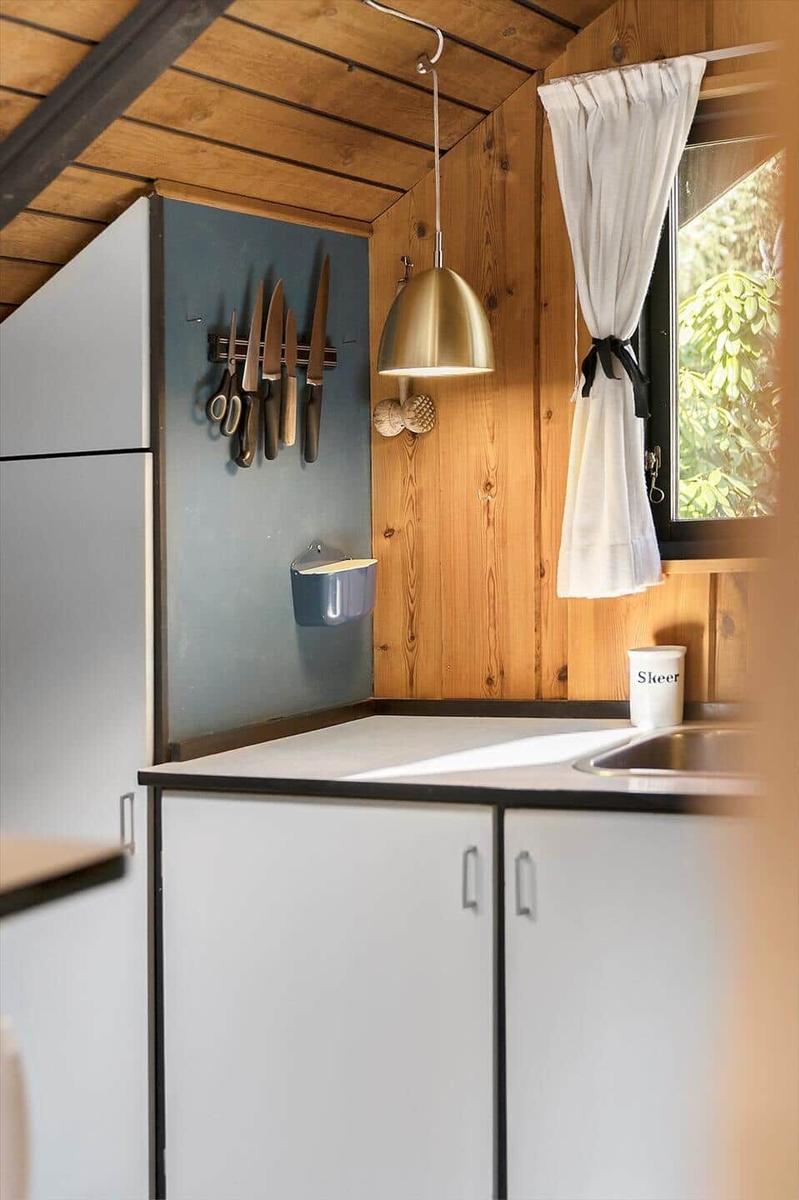 Küche mit Holzwand, Fenster, Küchenzeile und Hängeschneidemaschine.