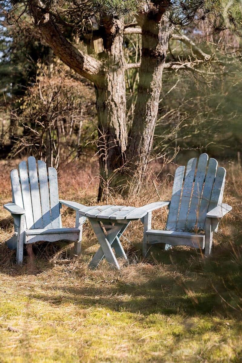 Zwei blaue Hocker und ein Tisch unter einem Baum im Freien.