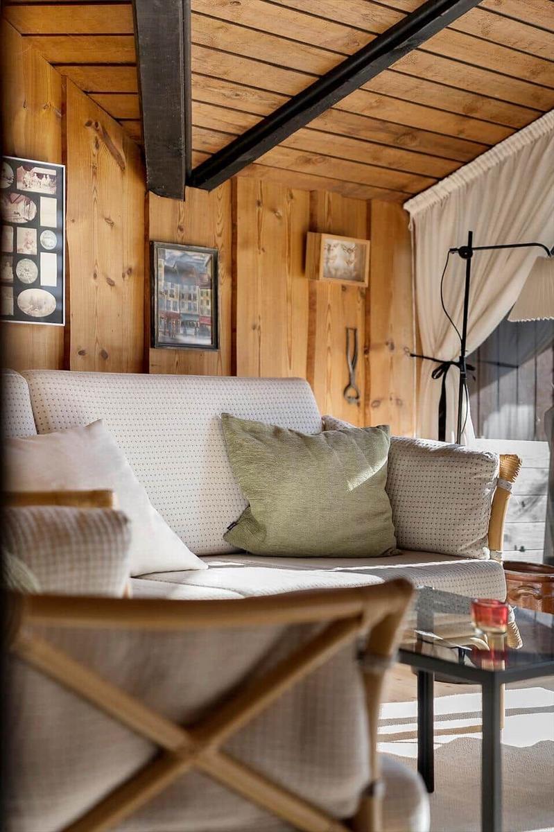 Wohnzimmer mit Holzwand, Sofa und Stehlampe.