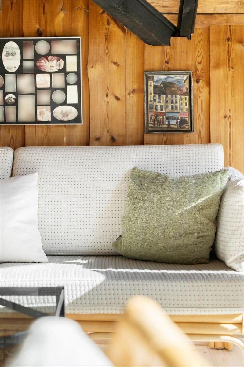 Sofa mit Kissen vor Holzwand mit Bildern