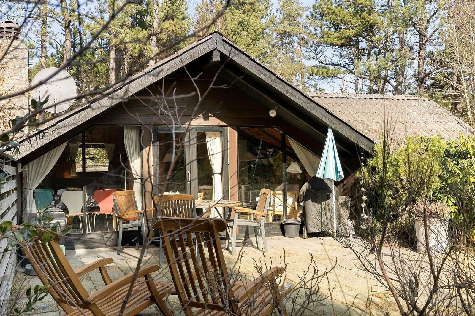 Haus mit Terrasse, Sitzgelegenheiten und Blick in den Wald.