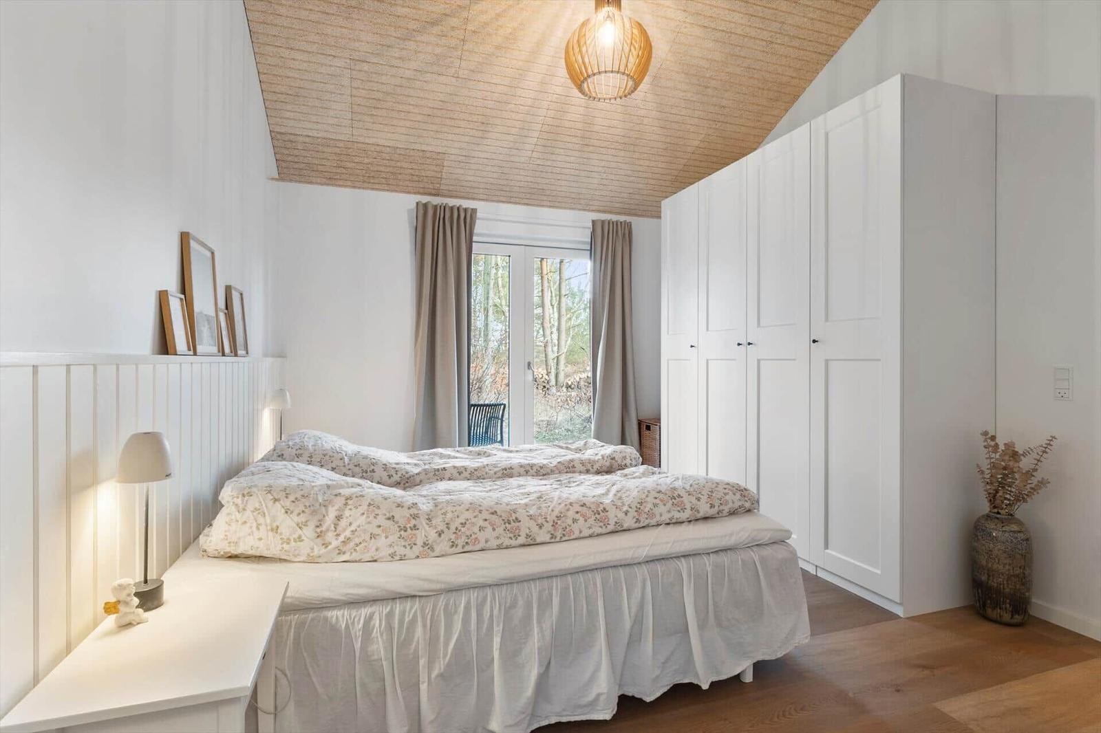 Bedroom with bed, closet, and window to the outside.