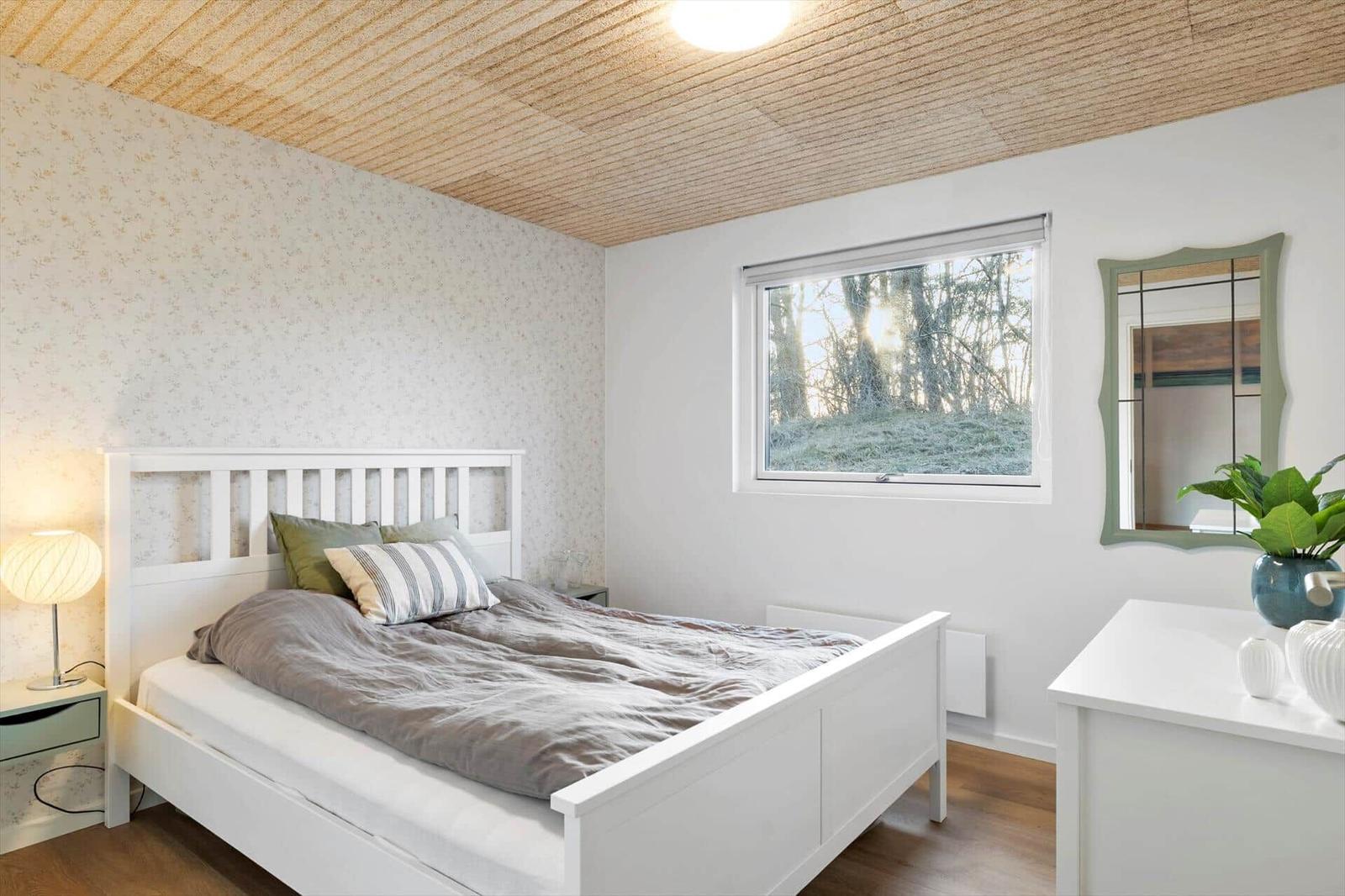 Bedroom with white bed, window, and mirror.