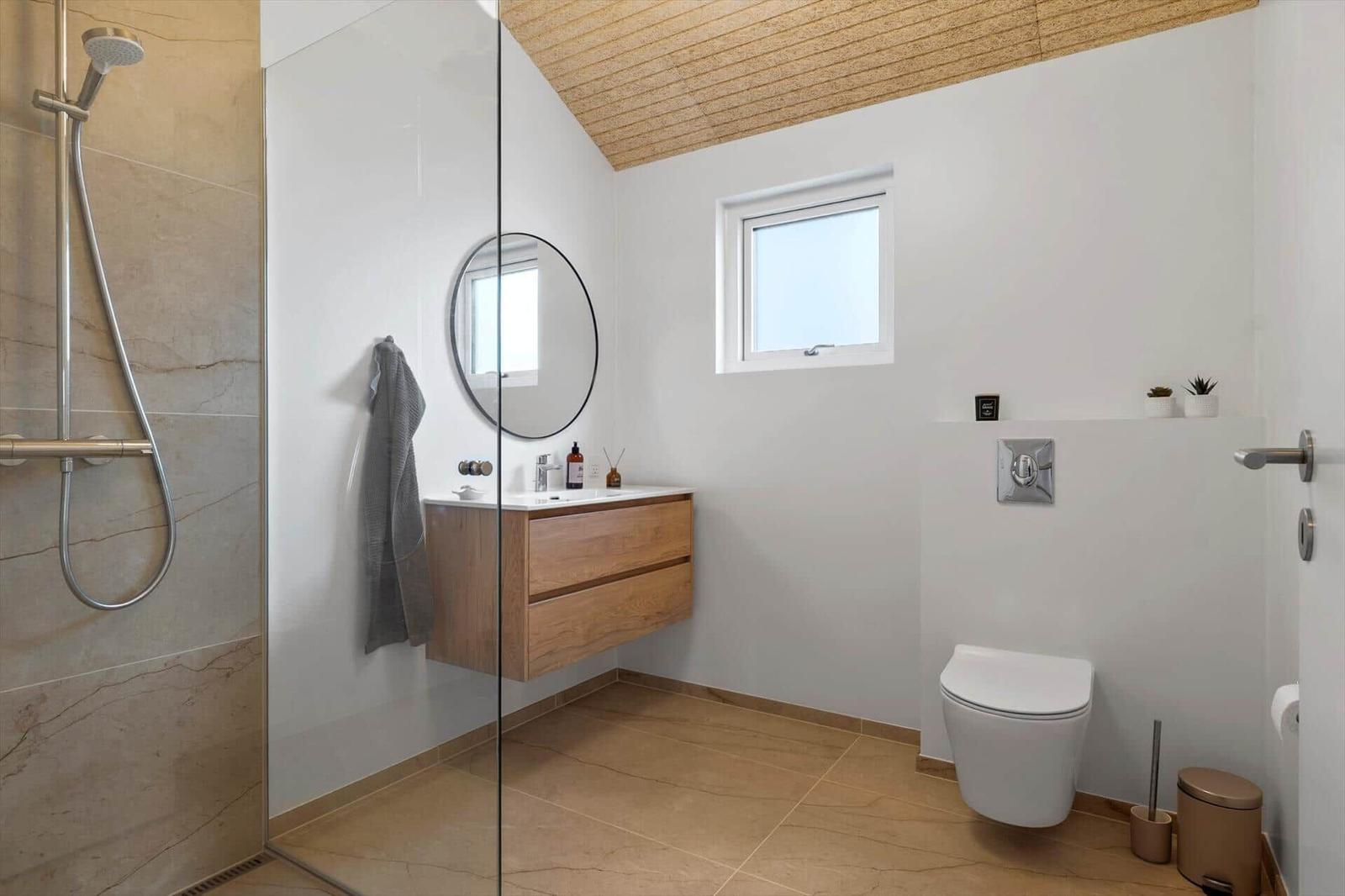 Bath with shower, sink, and toilet. Wooden ceiling and window.