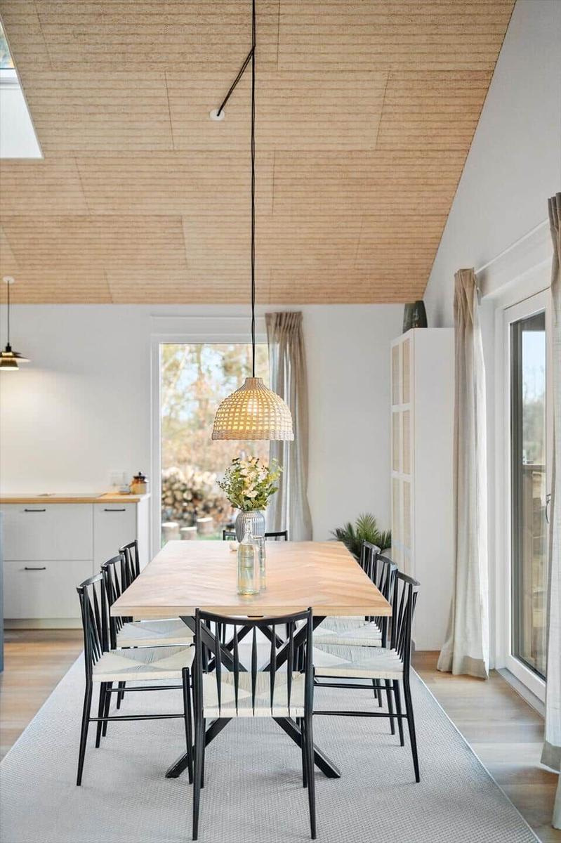 Dining area with wooden table, black chairs, and pendant lamp.