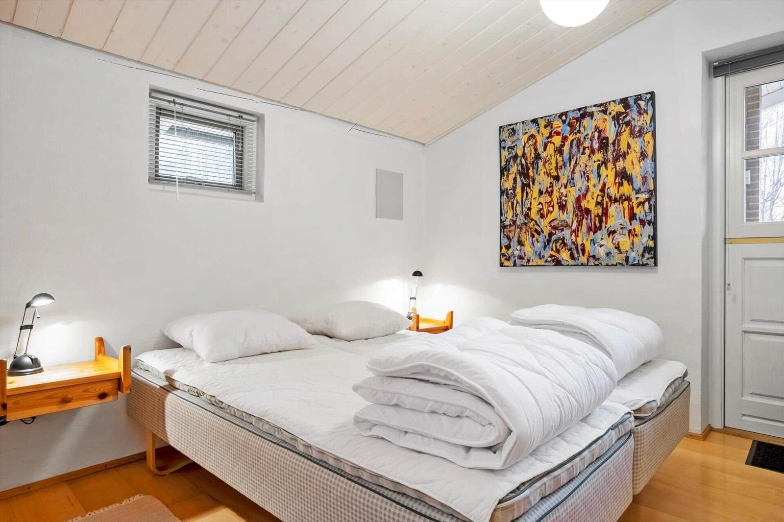 Schlafzimmer mit Bett, Nachttisch und Wandbild.