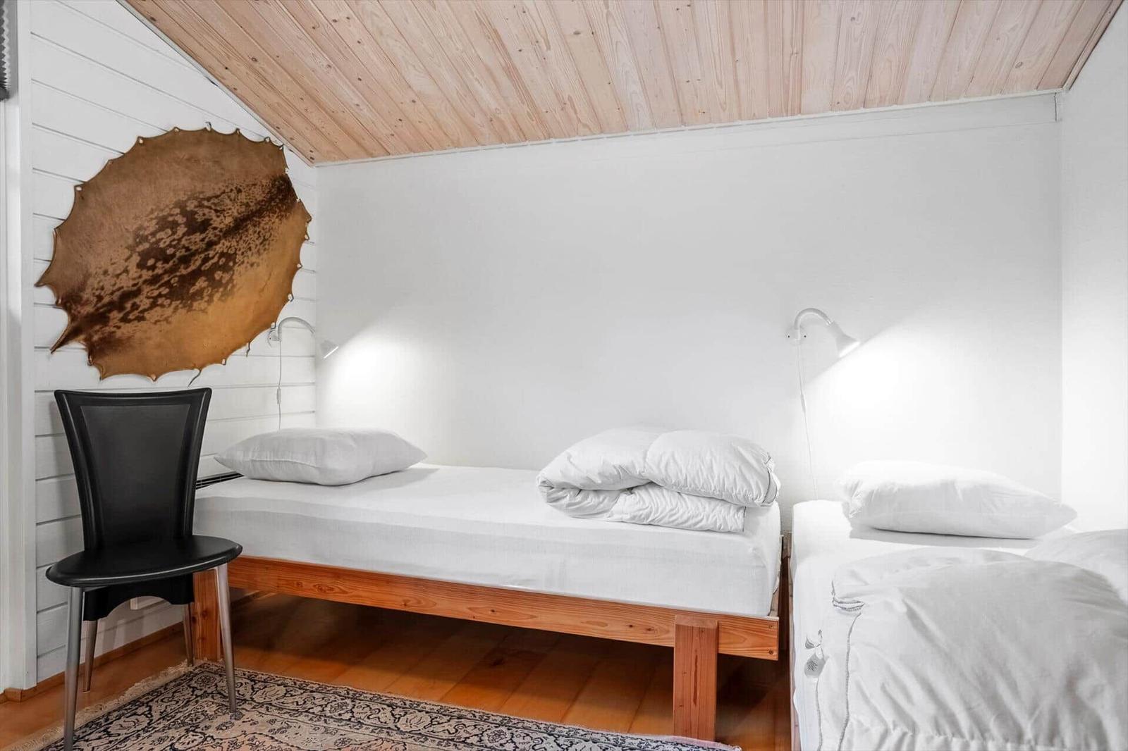 Zwei Betten mit weißen Bettwäschen unter einem Holzdach.