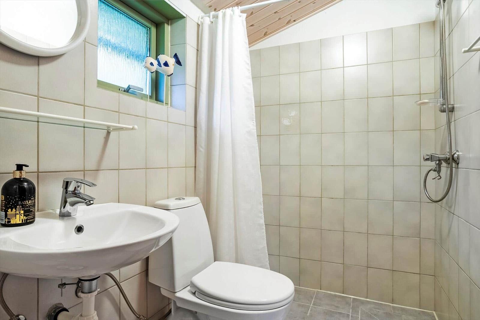 Badezimmer mit Dusche, Toilette und Waschbecken mit Spiegel.