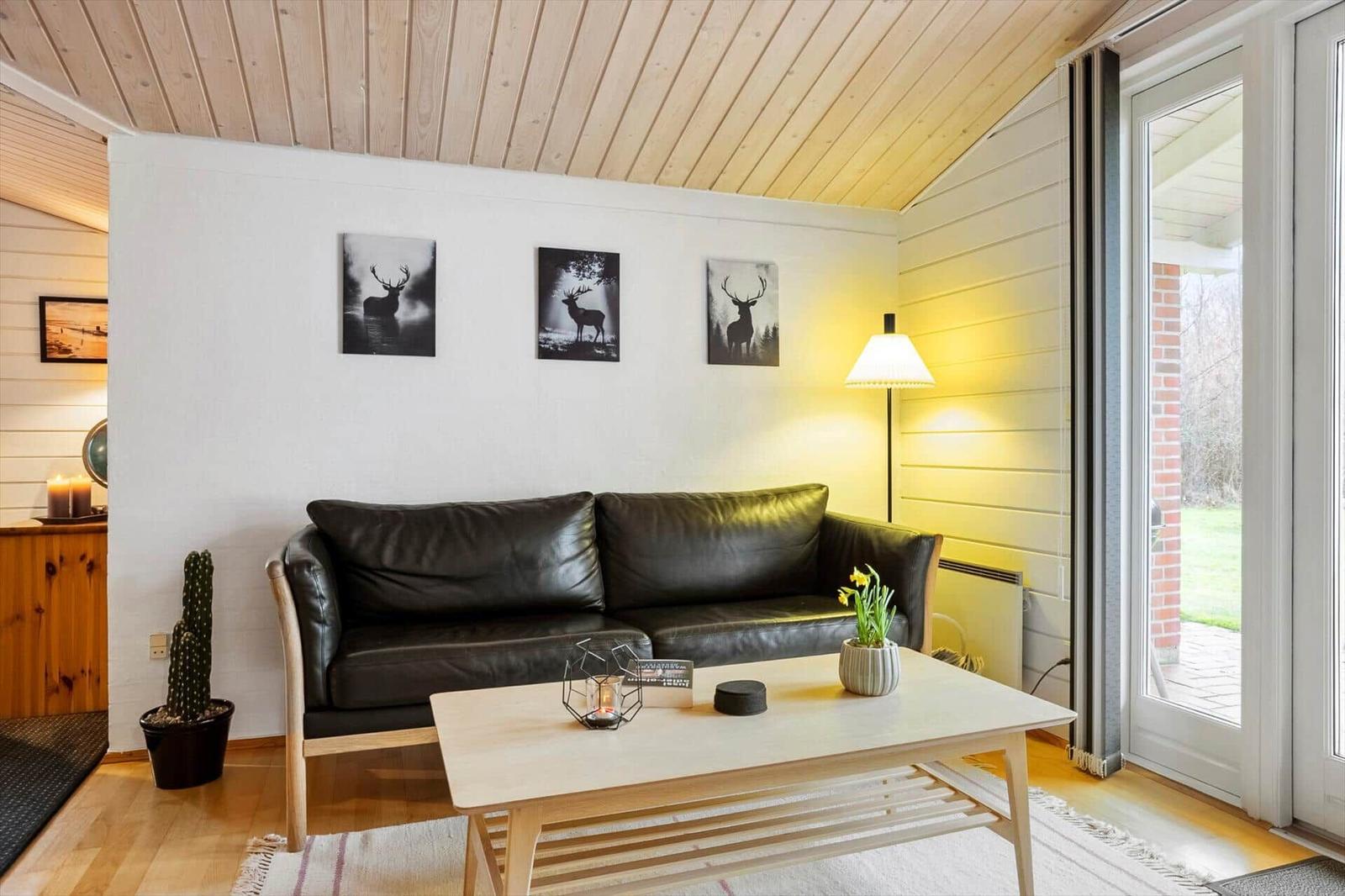 Wohnzimmer mit Sofa, Tisch und Fenster zur Außenterrasse.