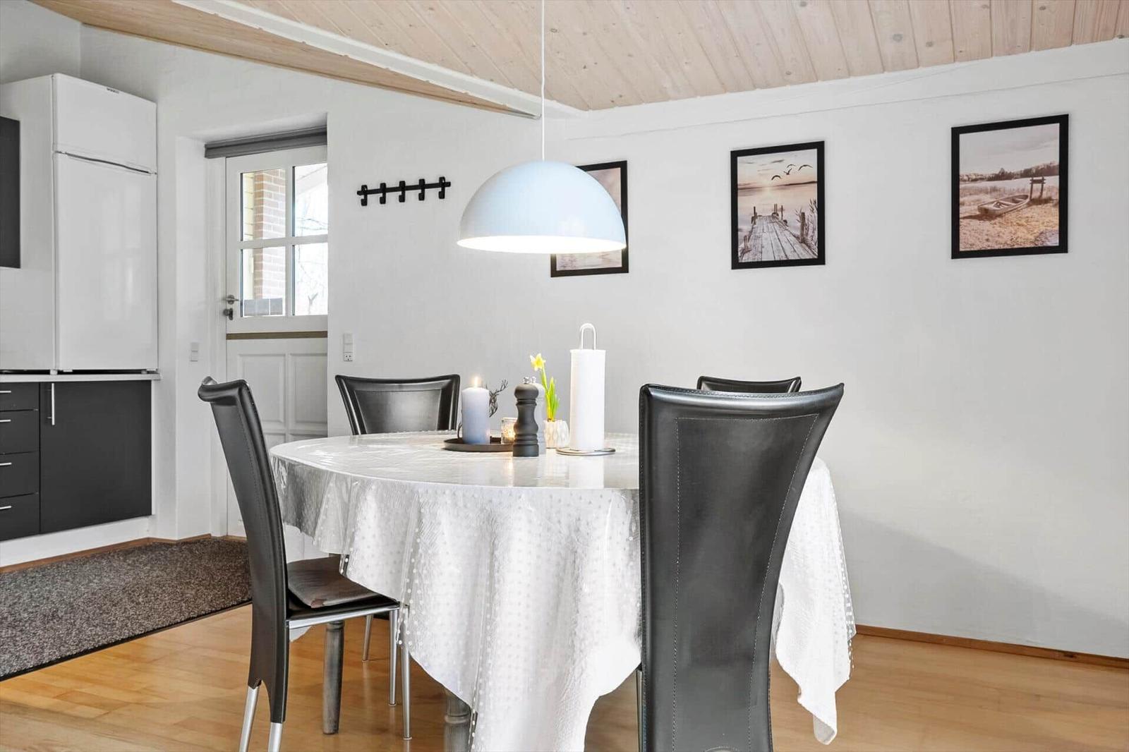 Esszimmer mit runden Tisch, schwarzen Stühlen und weißen Bildern an der Wand.