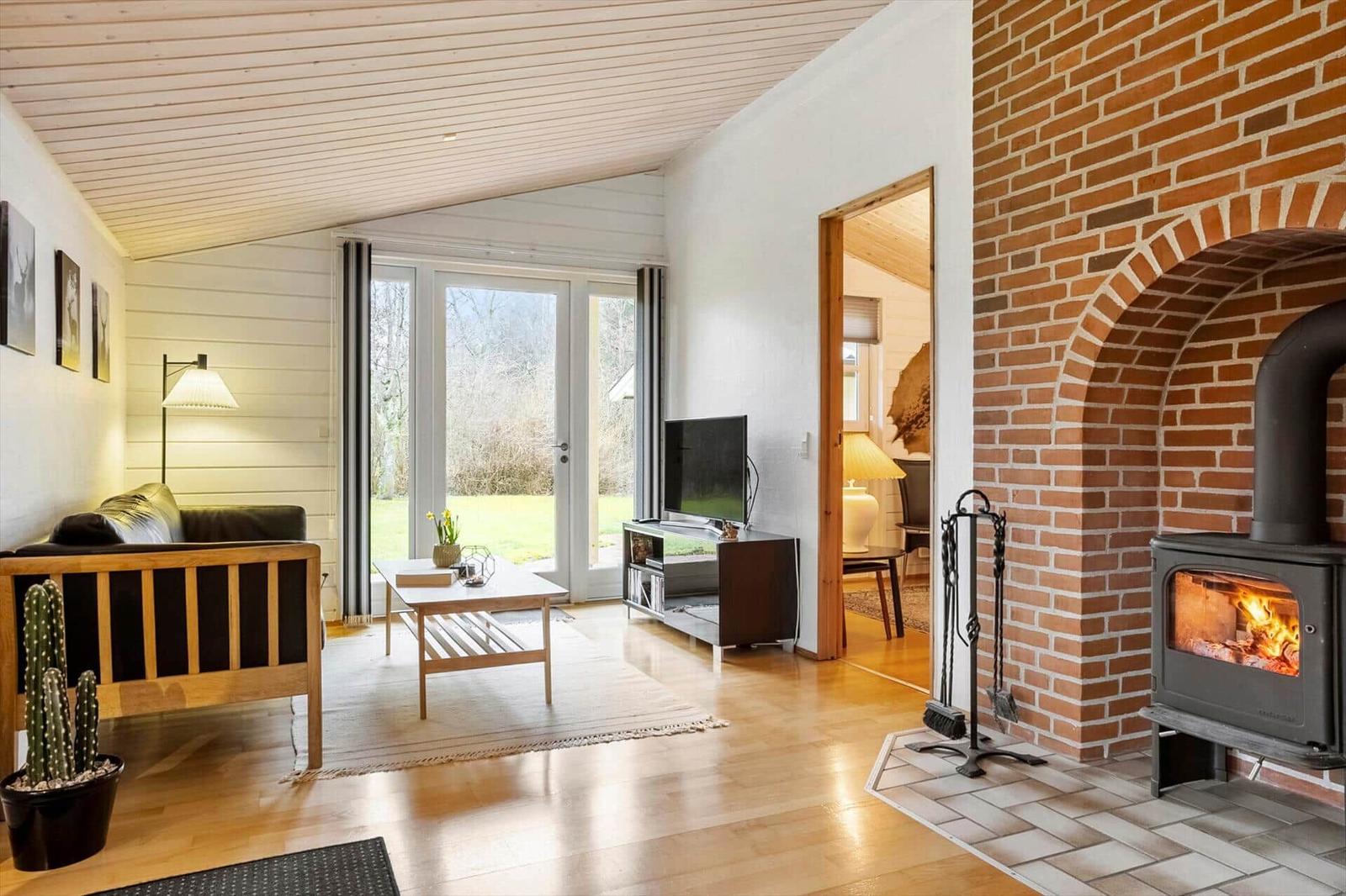 Wohnzimmer mit Kamin, Sofa, TV und Terrassentür.