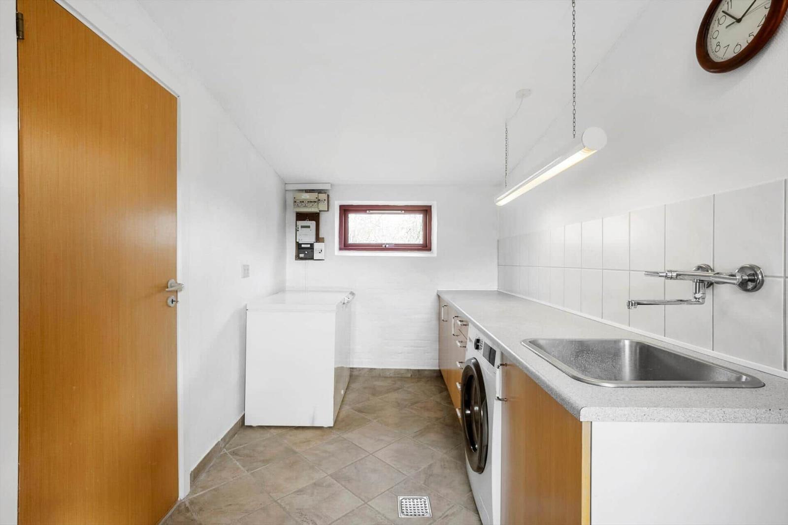 Laundry room with washing machine, sink, and small window.