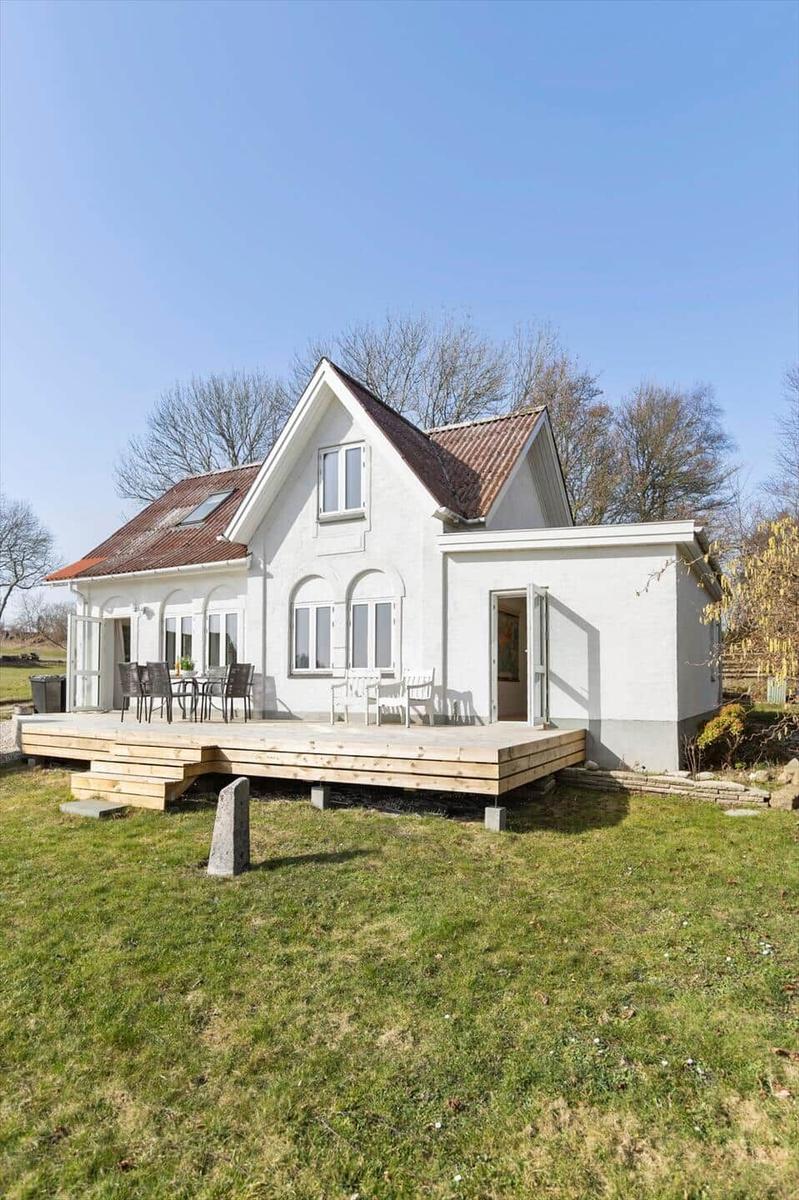 White house with terrace and garden. Wooden terrace with table and chairs.