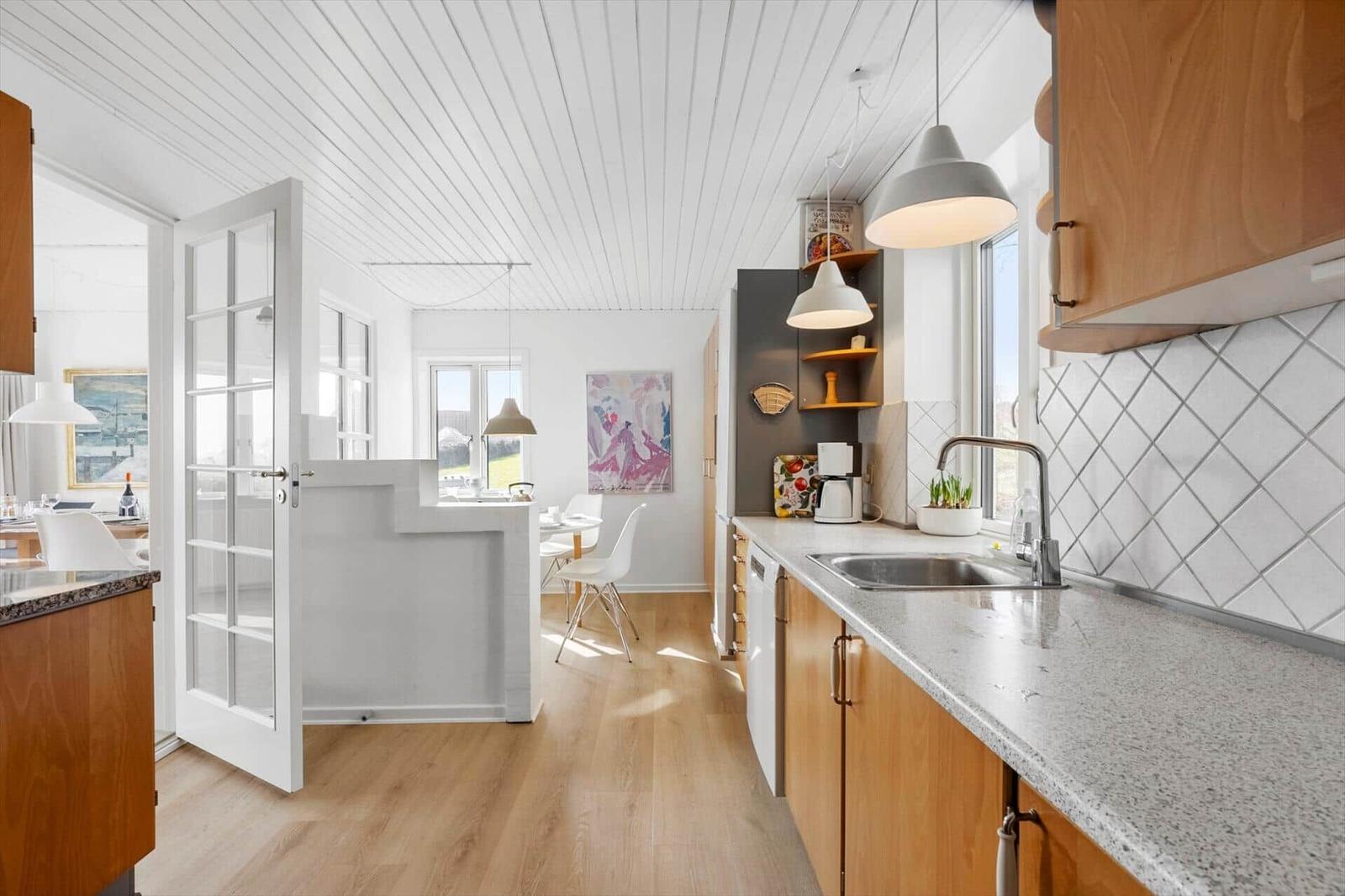 Kitchen with wooden cabinets and granite countertop. View into dining area with table and chairs.