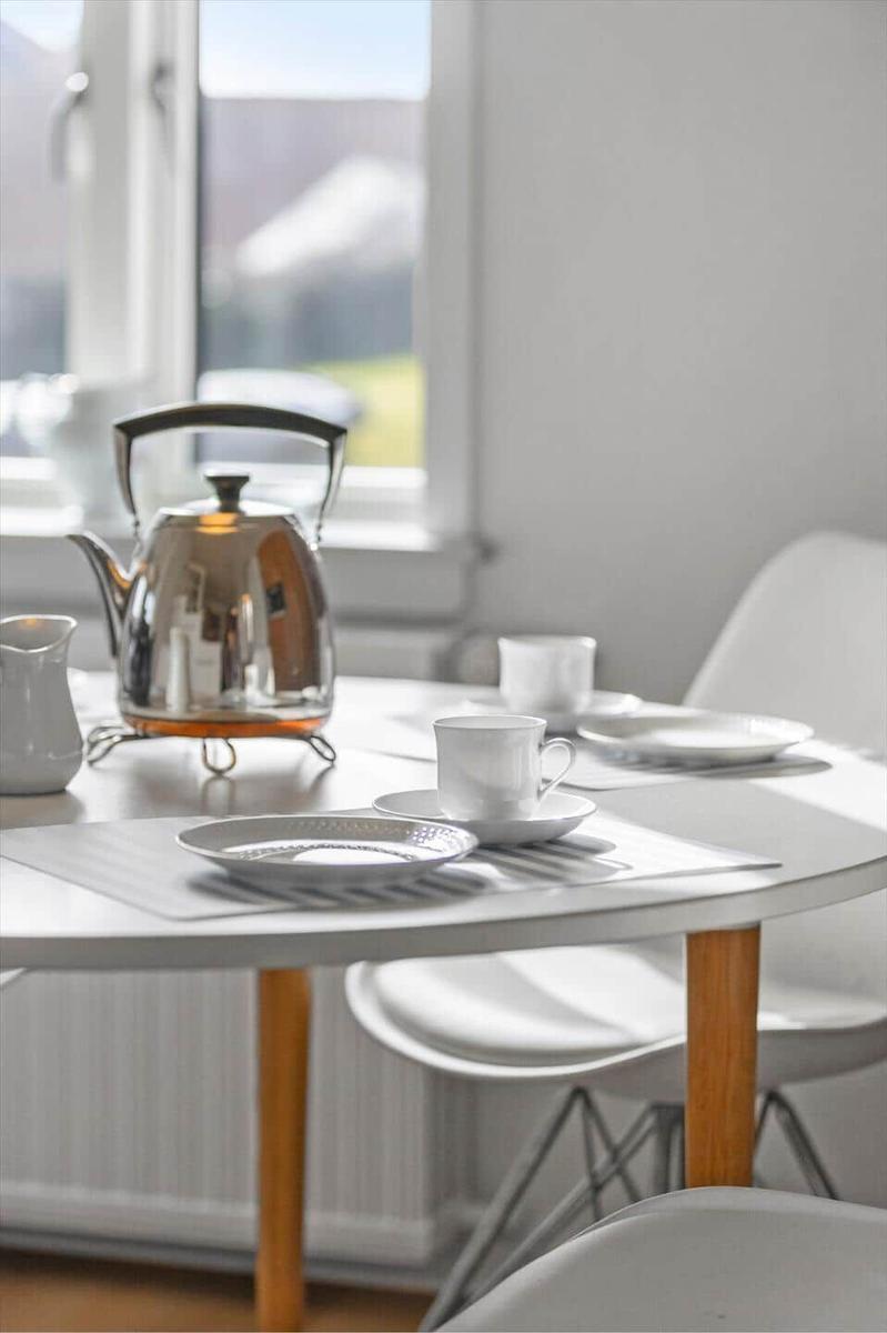 Table with cups, saucers, and kettle by window