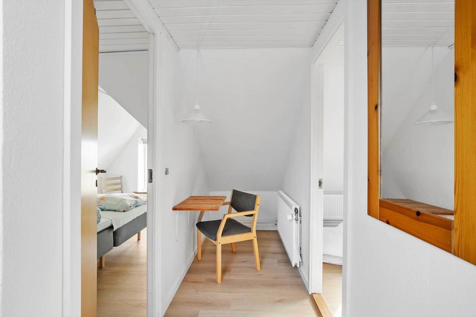 Hallway with table, chair, and view into bedroom and bathroom