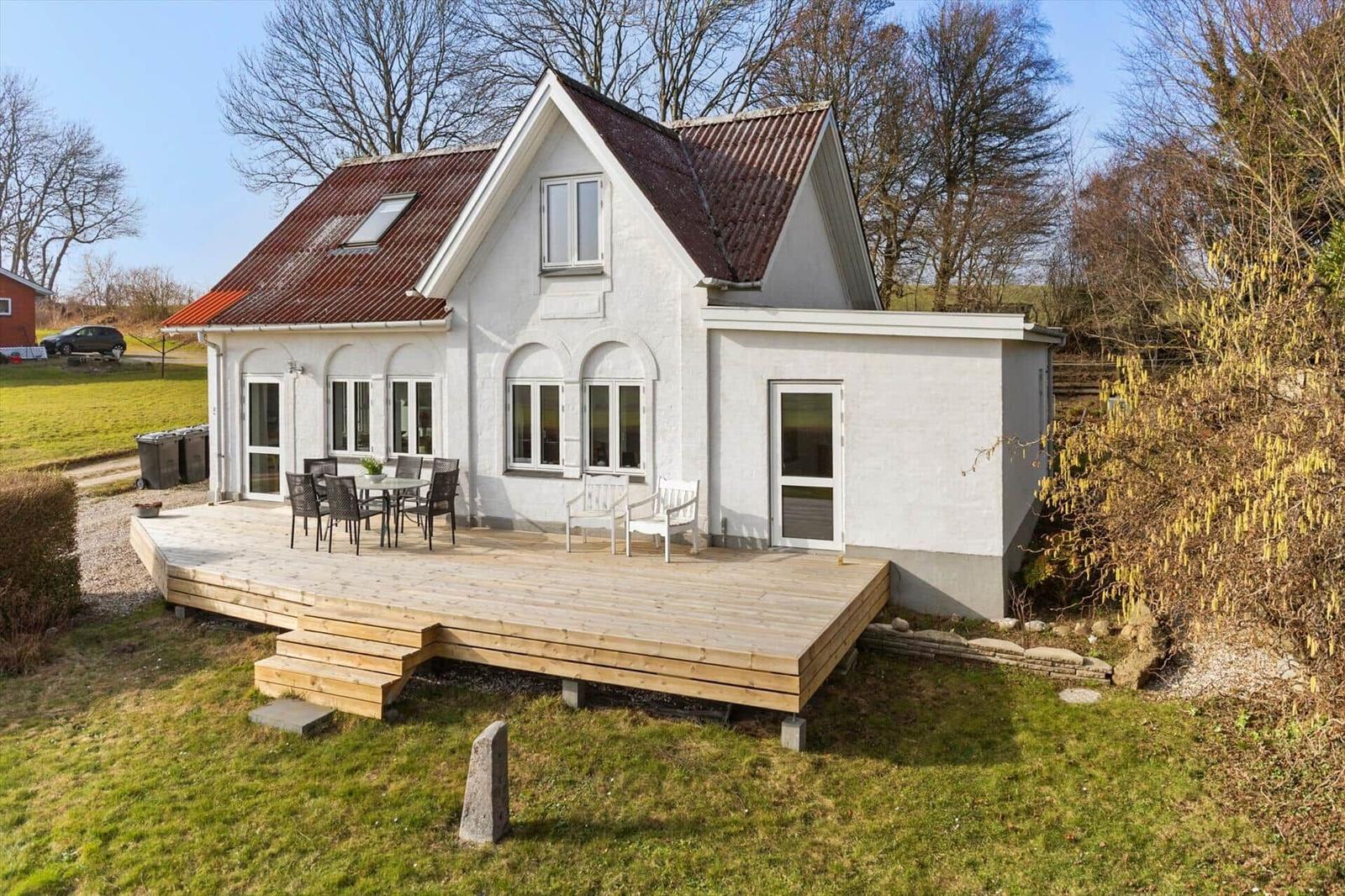 House with wooden terrace and garden. Outdoor seating area.