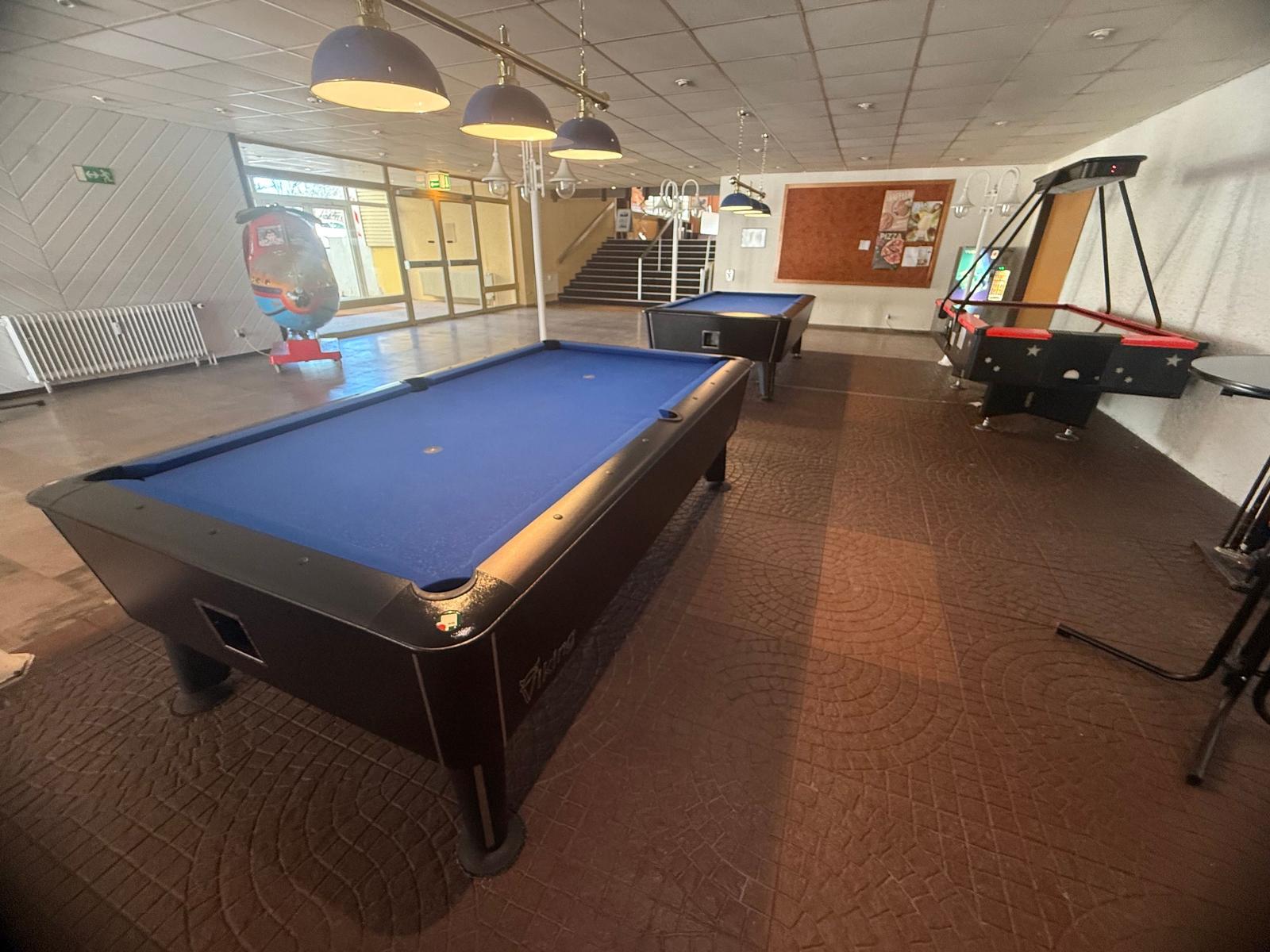 Raum mit zwei Billardtischen und einem Air-Hockey-Spielplatz.