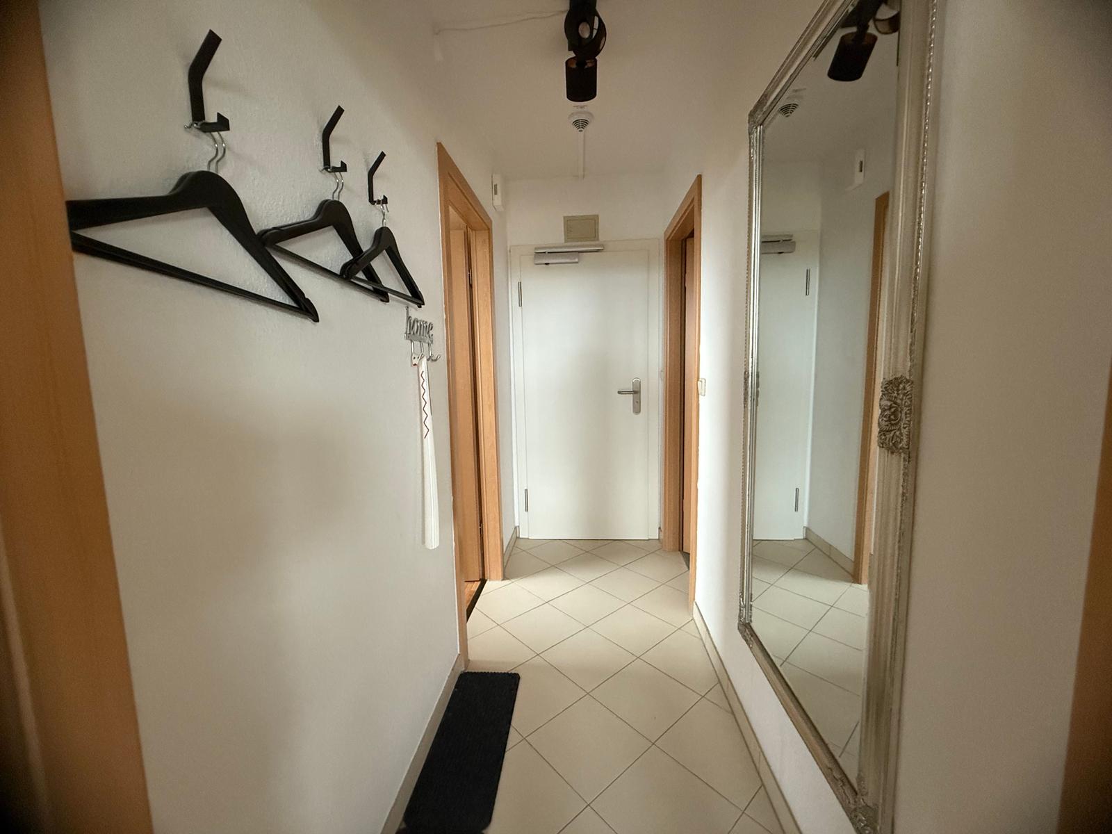 Flur mit Kleiderhaken, Spiegel und Bodenfliesen