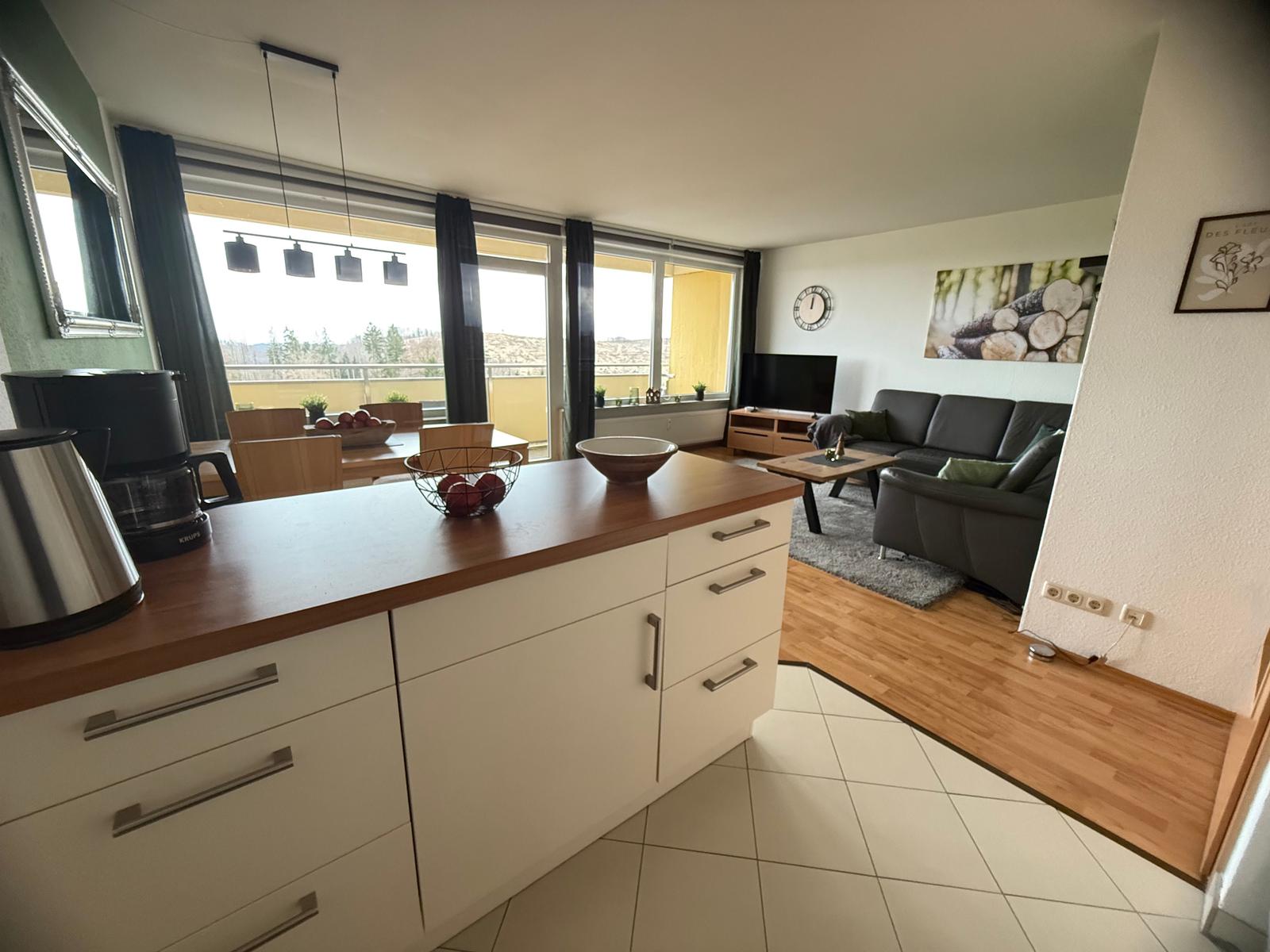 Küche mit Essbereich und Wohnzimmer mit Sofa und Balkon.