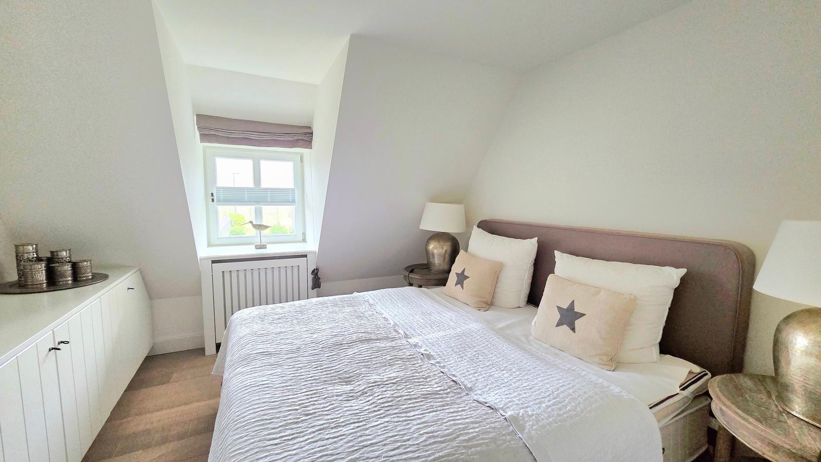 Schlafzimmer mit Bett, Nachttischen und Fenster