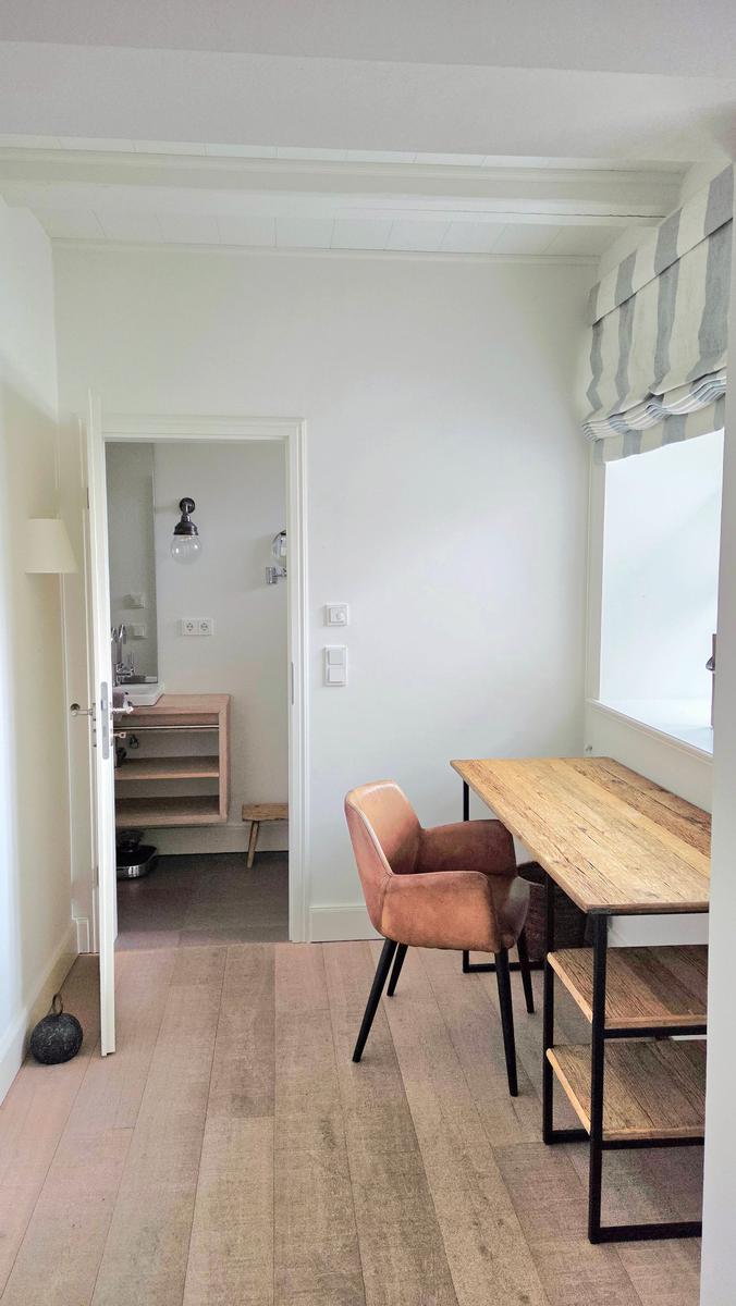 Essbereich mit Holztisch, Stuhl und Fenster. Durchgang zur Badewanne.